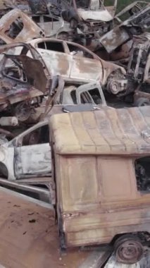 Bu stok dikey video Irpin, Bucha bölgesinde gri, düz, renksiz, yanmış arabaları gösteriyor.