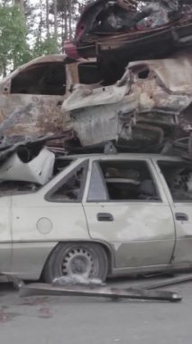 Bu stok dikey video Irpin, Bucha bölgesinde gri, düz, renksiz, yanmış arabaları gösteriyor.
