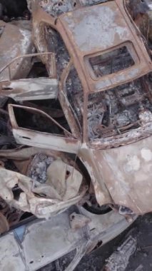 Bu stok dikey video Irpin, Bucha bölgesinde gri, düz, renksiz, yanmış arabaları gösteriyor.