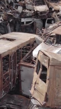 Bu stok dikey video Irpin, Bucha bölgesinde gri, düz, renksiz, yanmış arabaları gösteriyor.