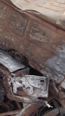Bu stok dikey video Irpin, Bucha bölgesinde gri, düz, renksiz, yanmış arabaları gösteriyor.