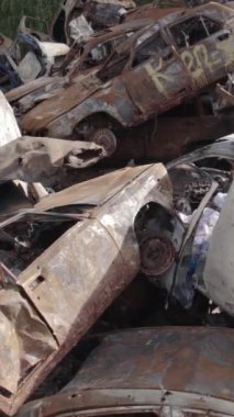 Bu stok dikey video Irpin, Bucha bölgesinde gri, düz, renksiz, yanmış arabaları gösteriyor.