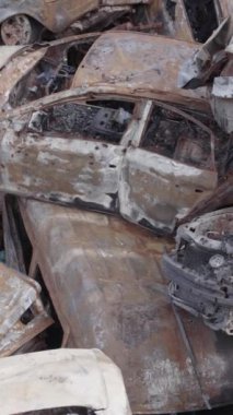 Bu stok dikey video Irpin, Bucha bölgesinde gri, düz, renksiz, yanmış arabaları gösteriyor.