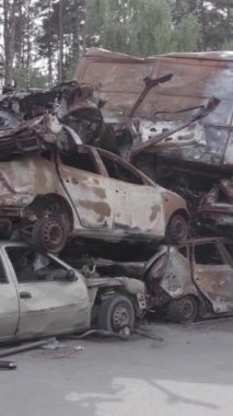 Bu stok dikey video Irpin, Bucha bölgesinde gri, düz, renksiz, yanmış arabaları gösteriyor.