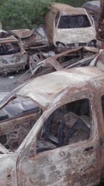 Bu stok dikey video Irpin, Bucha bölgesinde gri, düz, renksiz, yanmış arabaları gösteriyor.