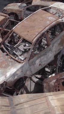 Bu stok dikey video Irpin, Bucha bölgesinde gri, düz, renksiz, yanmış arabaları gösteriyor.