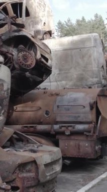Bu stok dikey video Irpin, Bucha bölgesinde gri, düz, renksiz, yanmış arabaları gösteriyor.