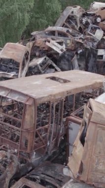 Bu stok dikey video Irpin, Bucha bölgesinde gri, düz, renksiz, yanmış arabaları gösteriyor.