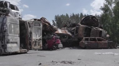 Bu video Irpin, Bucha bölgesinde, gri, düz, renksiz, yanmış arabaları gösteriyor.