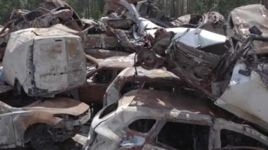 Bu video Irpin, Bucha bölgesinde, gri, düz, renksiz, yanmış arabaları gösteriyor.