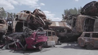 Bu video Irpin, Bucha bölgesinde, gri, düz, renksiz, yanmış arabaları gösteriyor.