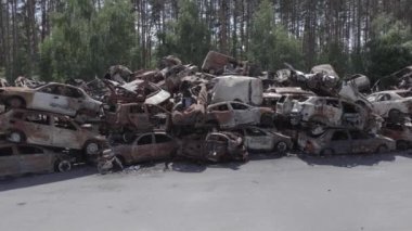 Bu video Irpin, Bucha bölgesinde, gri, düz, renksiz, yanmış arabaları gösteriyor.