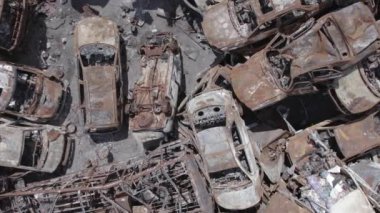 Bu video Irpin, Bucha bölgesinde, gri, düz, renksiz, yanmış arabaları gösteriyor.