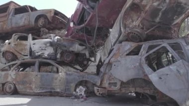 Bu video Irpin, Bucha bölgesinde, gri, düz, renksiz, yanmış arabaları gösteriyor.