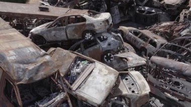 Bu video Irpin, Bucha bölgesinde, gri, düz, renksiz, yanmış arabaları gösteriyor.