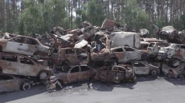 Bu video Irpin, Bucha bölgesinde, gri, düz, renksiz, yanmış arabaları gösteriyor.