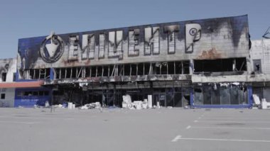 Bu video, Bucha 'daki bir alışveriş merkezinin yıkık dökük bir binasını gösteriyor. Ağır çekimde, gri, düz.