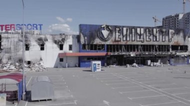 Bu video, Bucha 'daki bir alışveriş merkezinin yıkık dökük bir binasını gösteriyor. Ağır çekimde, gri, düz.