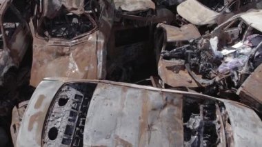 Bu video Ukrayna 'daki savaşın sonucunu gösteriyor. Yakılmış ve vurulmuş arabalar, gri, renksiz, düz.
