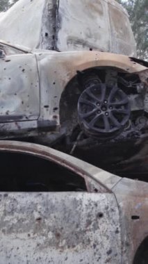 Bu stok dikey video Irpin, Bucha bölgesinde gri, düz, renksiz, yanmış arabaları gösteriyor.