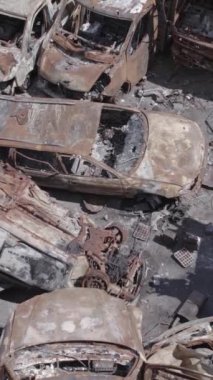 Bu stok dikey video Irpin, Bucha bölgesinde gri, düz, renksiz, yanmış arabaları gösteriyor.