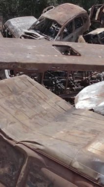 Bu stok dikey video Irpin, Bucha bölgesinde gri, düz, renksiz, yanmış arabaları gösteriyor.