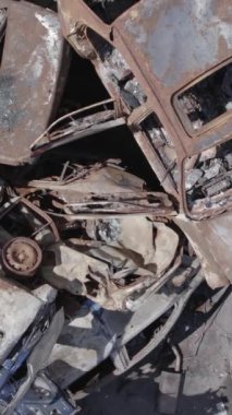 Bu stok dikey video Irpin, Bucha bölgesinde gri, düz, renksiz, yanmış arabaları gösteriyor.