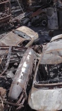 Bu stok dikey video Irpin, Bucha bölgesinde gri, düz, renksiz, yanmış arabaları gösteriyor.