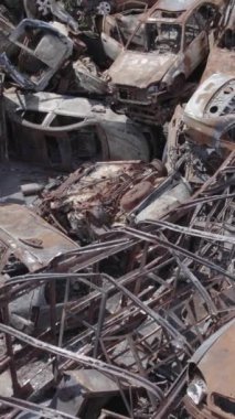 Bu stok dikey video Irpin, Bucha bölgesinde gri, düz, renksiz, yanmış arabaları gösteriyor.