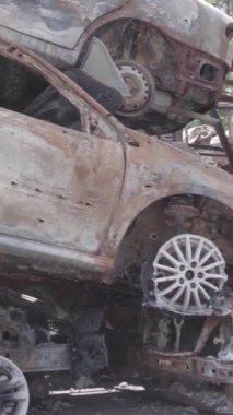 Bu stok dikey video Irpin, Bucha bölgesinde gri, düz, renksiz, yanmış arabaları gösteriyor.