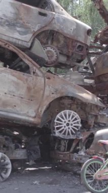 Bu stok dikey video Irpin, Bucha bölgesinde gri, düz, renksiz, yanmış arabaları gösteriyor.