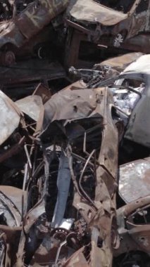 Bu stok dikey video Irpin, Bucha bölgesinde gri, düz, renksiz, yanmış arabaları gösteriyor.