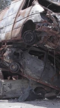 Bu stok dikey video Irpin, Bucha bölgesinde gri, düz, renksiz, yanmış arabaları gösteriyor.