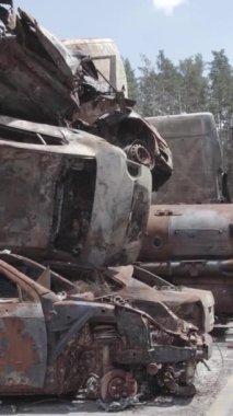 Bu stok dikey video Irpin, Bucha bölgesinde gri, düz, renksiz, yanmış arabaları gösteriyor.