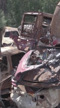 Bu stok dikey video Irpin, Bucha bölgesinde gri, düz, renksiz, yanmış arabaları gösteriyor.