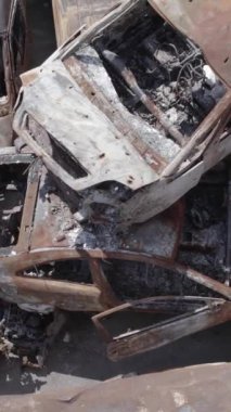 Bu stok dikey video Irpin, Bucha bölgesinde gri, düz, renksiz, yanmış arabaları gösteriyor.