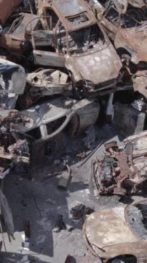 Bu stok dikey video Irpin, Bucha bölgesinde gri, düz, renksiz, yanmış arabaları gösteriyor.