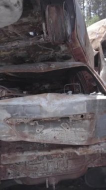 Bu stok dikey video Irpin, Bucha bölgesinde gri, düz, renksiz, yanmış arabaları gösteriyor.