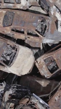 Bu stok dikey video Irpin, Bucha bölgesinde gri, düz, renksiz, yanmış arabaları gösteriyor.