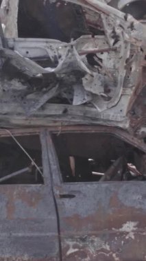 Bu stok dikey video Irpin, Bucha bölgesinde gri, düz, renksiz, yanmış arabaları gösteriyor.