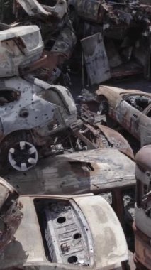 Bu stok dikey video Irpin, Bucha bölgesinde gri, düz, renksiz, yanmış arabaları gösteriyor.