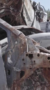 Bu stok dikey video Irpin, Bucha bölgesinde gri, düz, renksiz, yanmış arabaları gösteriyor.