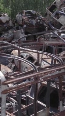 Bu stok dikey video Irpin, Bucha bölgesinde gri, düz, renksiz, yanmış arabaları gösteriyor.