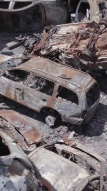 Bu stok dikey video Irpin, Bucha bölgesinde gri, düz, renksiz, yanmış arabaları gösteriyor.