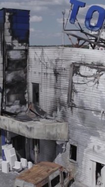 Bu stok dikey video, Bucha 'daki bir alışveriş merkezinin yıkık dökük bir binasını gösteriyor. Ağır çekim, gri, renksiz, düz.