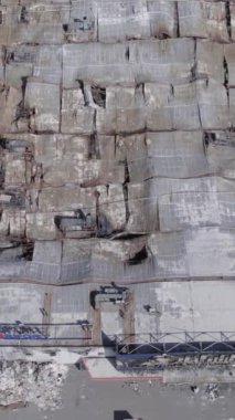 This stock vertical video shows a destroyed building of a shopping center in Bucha, slow motion, grey, no color, flat