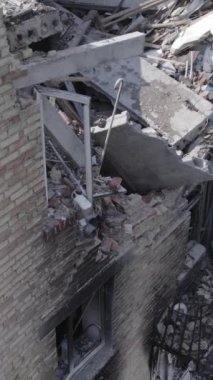 This stock vertical video shows a destroyed building in the city of Makariv during the war in Ukraine, grey, no color, flat