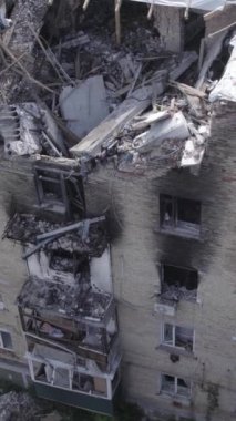 This stock vertical video shows a destroyed building in the city of Makariv during the war in Ukraine, grey, no color, flat