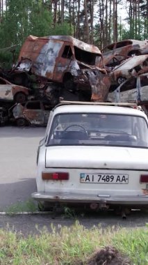 Bu stok dikey video Irpin, Bucha bölgesinde bir kurşun ve yanmış araba dökümü gösteriyor.