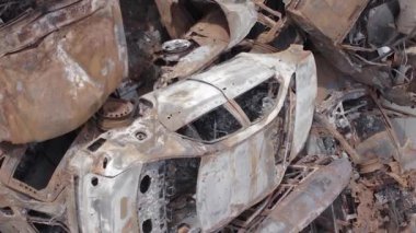 Bu stok dikey video Irpin, Bucha bölgesinde gri, düz, renksiz, yanmış arabaları gösteriyor.